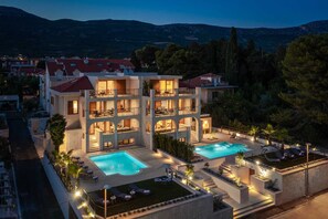 A multi-story hotel with a swimming pool and outdoor seating area. - Beachfront Villa Anemona with Pool (Kaštel Stari)