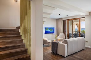 Un salon moderne avec un canapé, un téléviseur et une vue sur la mer.