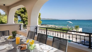 A terrace with a table set for breakfast, overlooking a sea view. - Beachfront Villa Armeria with Pool (Kaštel Stari)