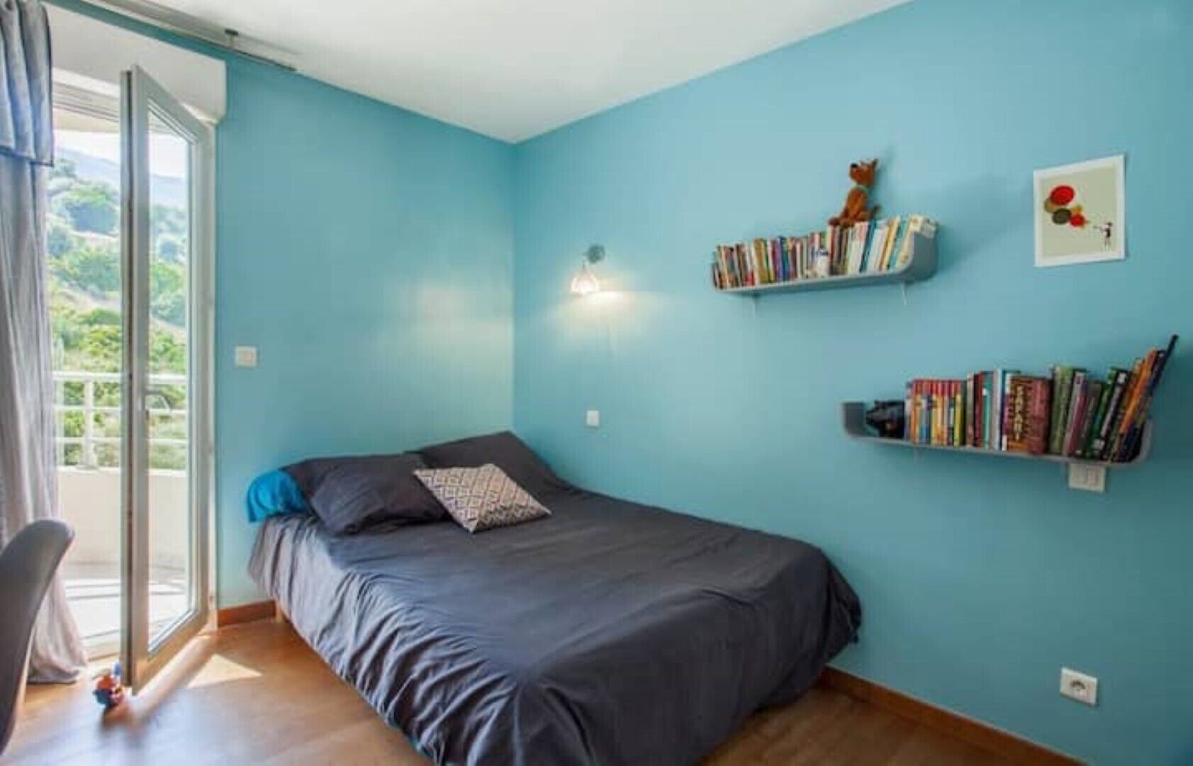 Un dormitorio con cama, una estantería y una ventana.