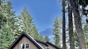Een houten chalet met twee verdiepingen, een stenen fundering, twee garagepoorten en een stenen trap naar de ingang.