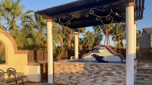 A covered patio area with a mosaic pool, palm trees, and outdoor furniture. - Honeymoon suite with private jacuzzi DISCOUNTED RATE (Loreto)
