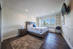 A bedroom with a bed, bedside tables, a TV, and a window with a view.
