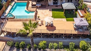 A residential property with a swimming pool, patio, and a covered outdoor seating area.