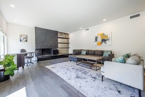 Un salon moderne avec une cheminée, un canapé, une table basse et une plante en pot.