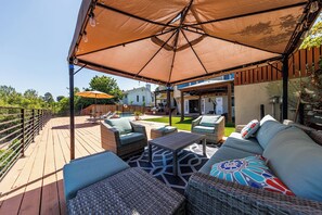 A covered outdoor patio with wicker furniture, a pool, and a view of a house.