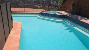 A swimming pool with a tiled edge, surrounded by a fence and a wooden wall.