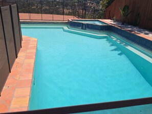 A swimming pool with a tiled edge, surrounded by a fence and a wooden wall.