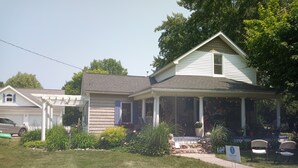 A house with a porch, a small garden, and a sign indicating a porchfest. - UPPER 3 rm.  studio B&B steps from beach & farm markt/shop'g.; dogs ok w/fee.  (Port Austin)