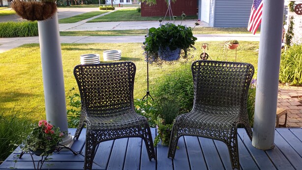 A covered porch with two wicker chairs, a hanging basket, and a potted plant. - UPPER 3 rm.  studio B&B steps from beach & farm markt/shop'g.; dogs ok w/fee.  (Port Austin)