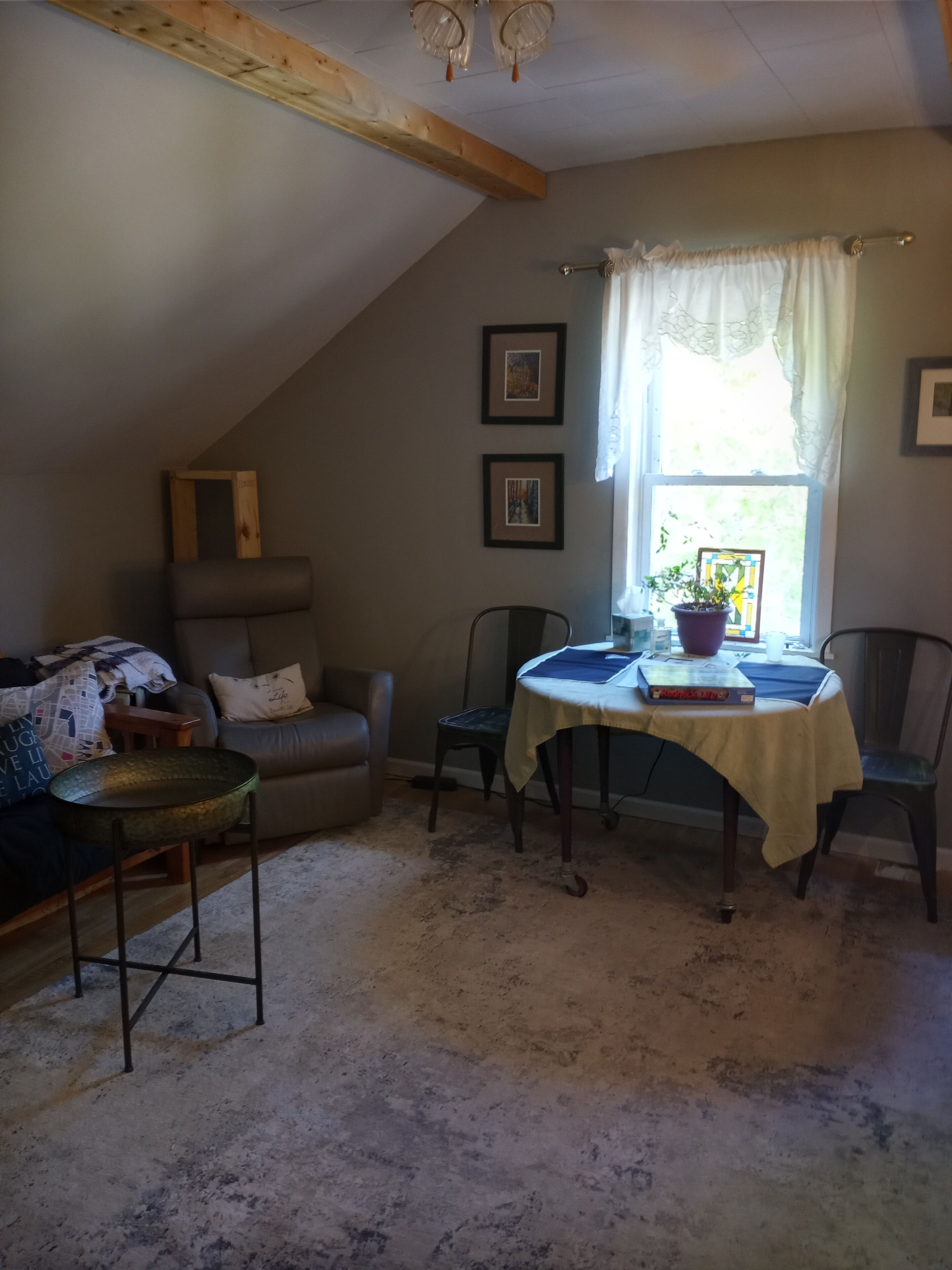 Ein gemütliches Wohnzimmer mit hohen Decken, einem Esstisch mit Stühlen, einer Couch und einem Fenster mit Vorhängen.