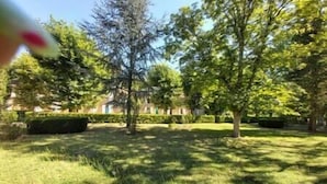 Un parc avec des arbres et un bâtiment en arrière-plan.