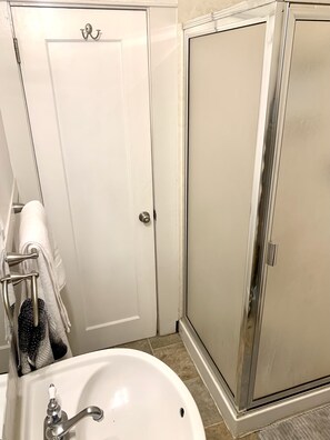 Une salle de bain avec un lavabo blanc, un porte-serviettes et un espace douche.