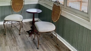 Een hoekkamer met twee rieten stoelen en een kleine ronde tafel.