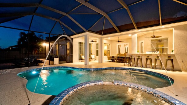 A swimming pool with a covered patio area, a bar, and a dining area. - Luxury 4 BR/3BA Waterview Home w/ Pool + Spa with work space (Bradenton)