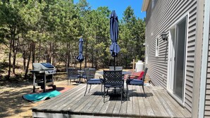 Een terras met buitenmeubilair, een barbecue en een overdekt gedeelte met parasols.