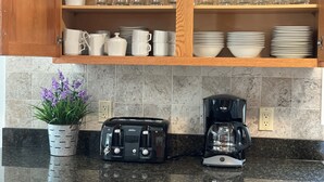 Een keuken met een broodrooster, koffiezetapparaat en een bloempot.