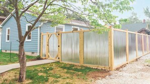 En bostadsfastighet med en inhägnad trädgård, en träport och ett hus med blå fasad.