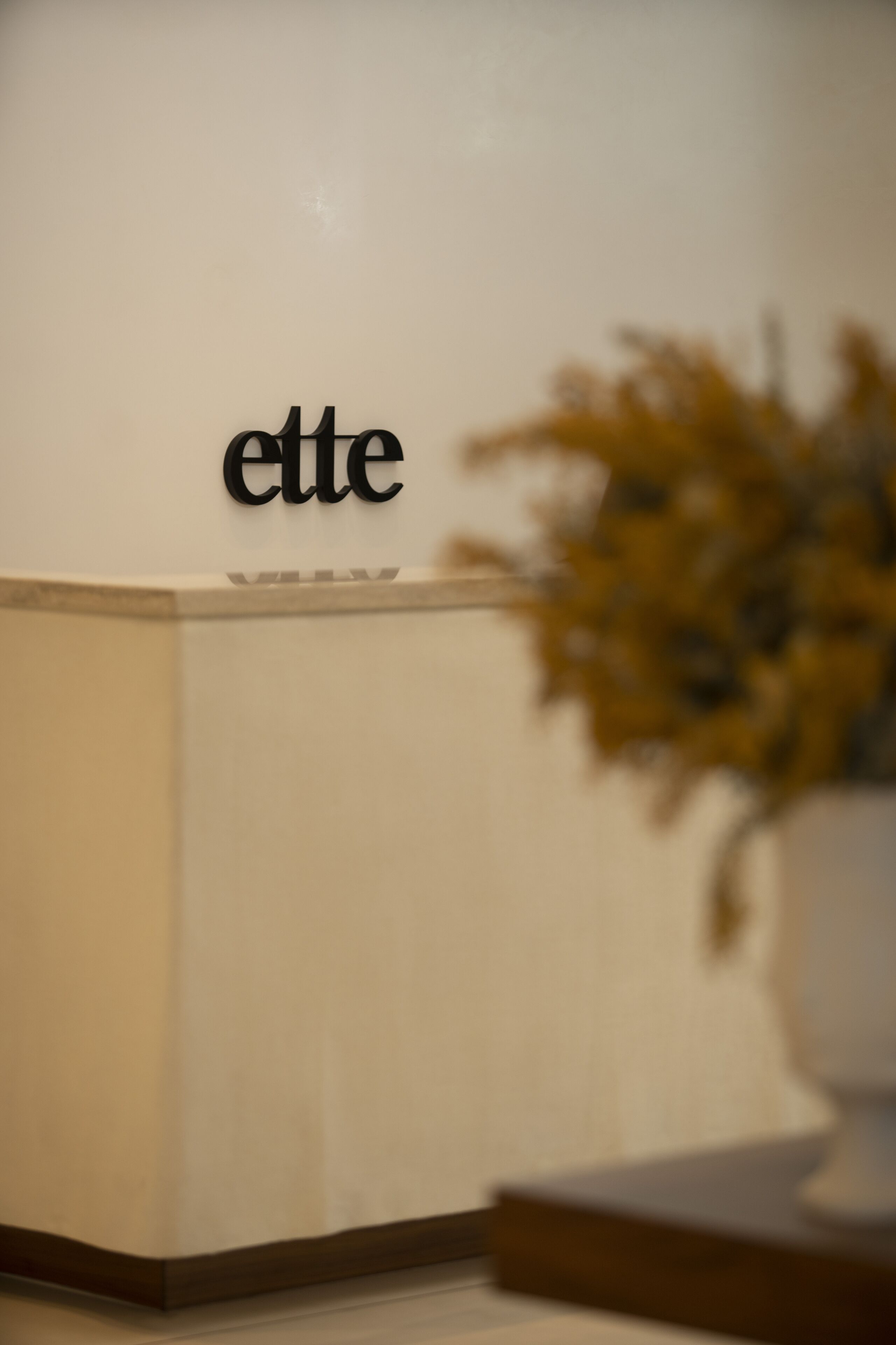 Una reception con la scritta "ette", un vaso di fiori e uno sfondo sfocato.