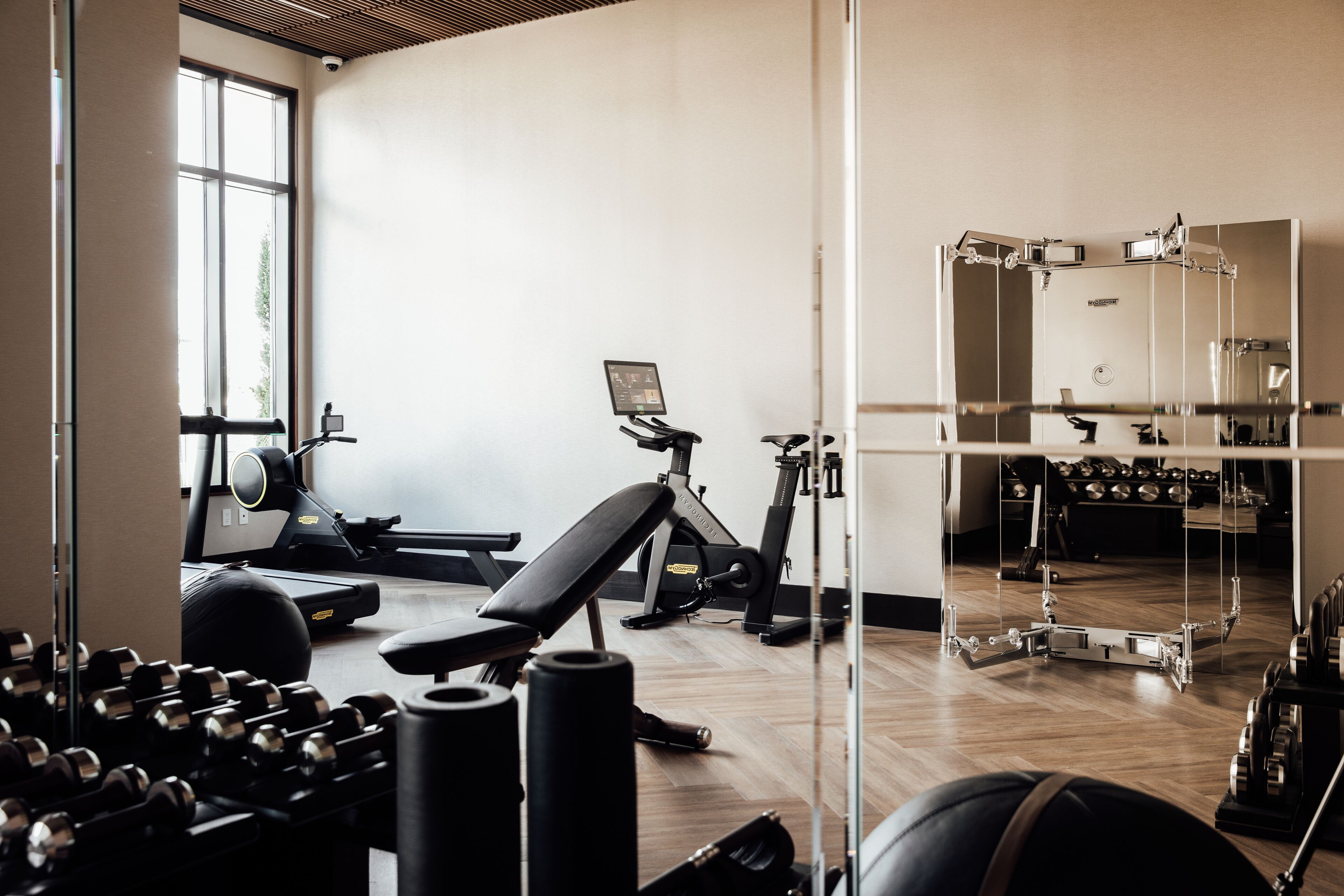 Uma academia com equipamentos de ginástica, esteira e banco.