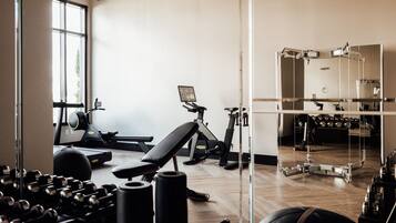 Uma academia com equipamentos de ginástica, esteira e banco.