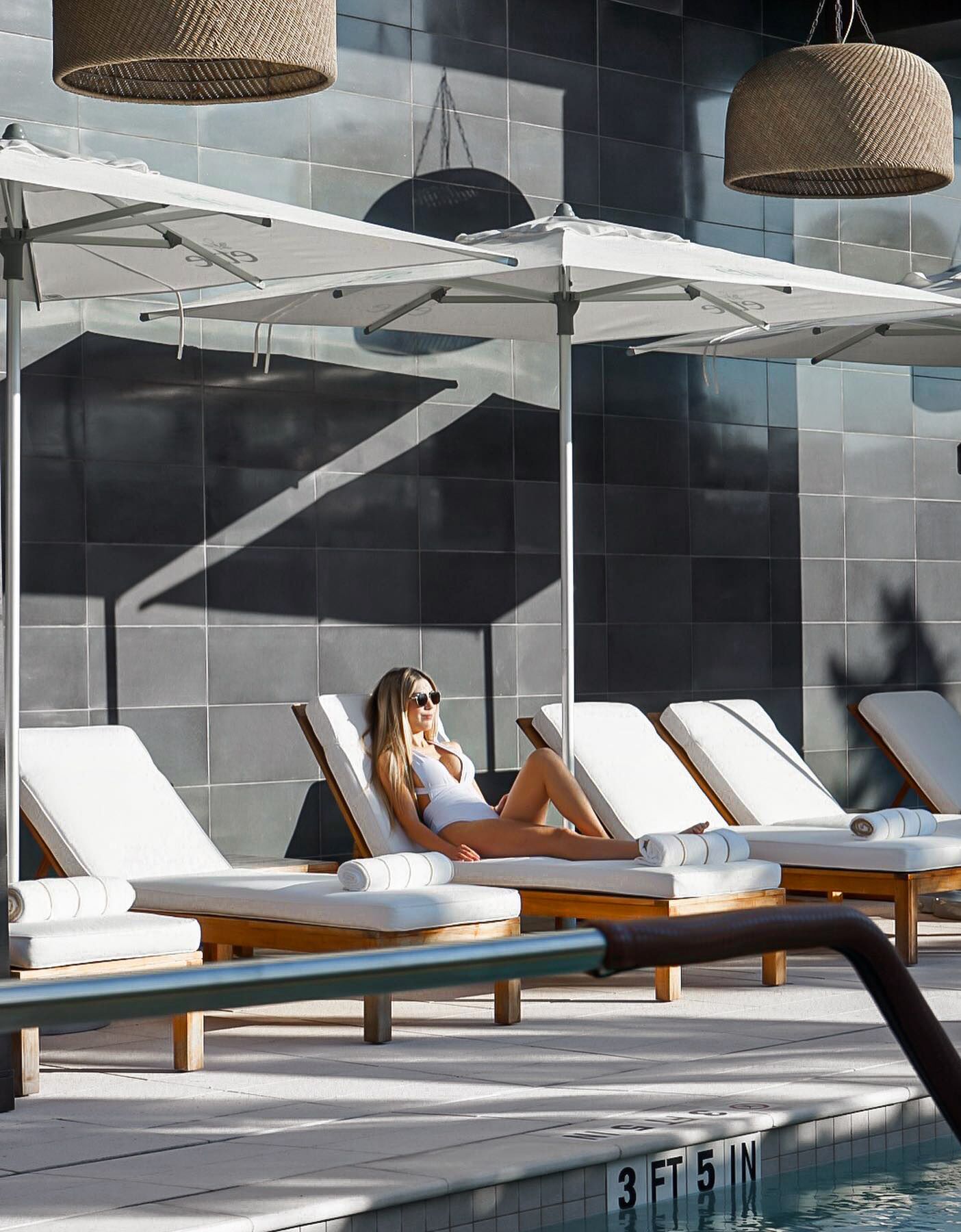 Un'area a bordo piscina con lettini e una zona relax all'ombra.