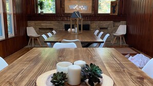 A dining area with a wooden table, white chairs, a chandelier, and a stone fireplace. - Private Retreat For You w/HEATED Pool, Private Dock,  Activity gym, 100 acres! (Galena)