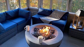 A cozy seating area with blue sofas and a central fire pit. - Private Retreat For You w/HEATED Pool, Private Dock,  Activity gym, 100 acres! (Galena)