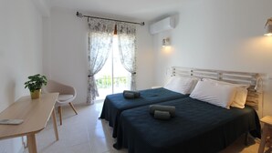 Ein Schlafzimmer mit zwei Betten, einem Schreibtisch, einem Stuhl und einer Topfpflanze.