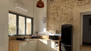 Une cuisine moderne avec un mur en pierre, un réfrigérateur noir et une fenêtre laissant entrer la lumière naturelle.
