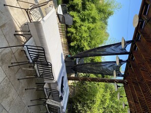 An outdoor patio with a dining table and chairs, surrounded by greenery and a wooden fence. - Character house | Uzès & Pont du Gard (Saint Maximin)