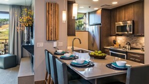 Una cocina moderna con armarios de madera oscura, electrodomésticos de acero inoxidable y una isla central con vajilla azul y blanca.