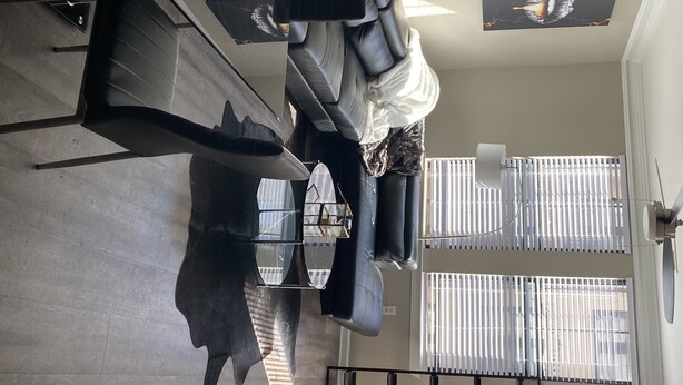 Uma sala de estar moderna com um sofá, uma mesa de centro e uma janela grande com persianas.