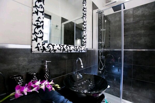 A modern bathroom with a black vessel sink, a large mirror, and a shower area. - Elegant double room with a balcony and a view of the dome (Roma)