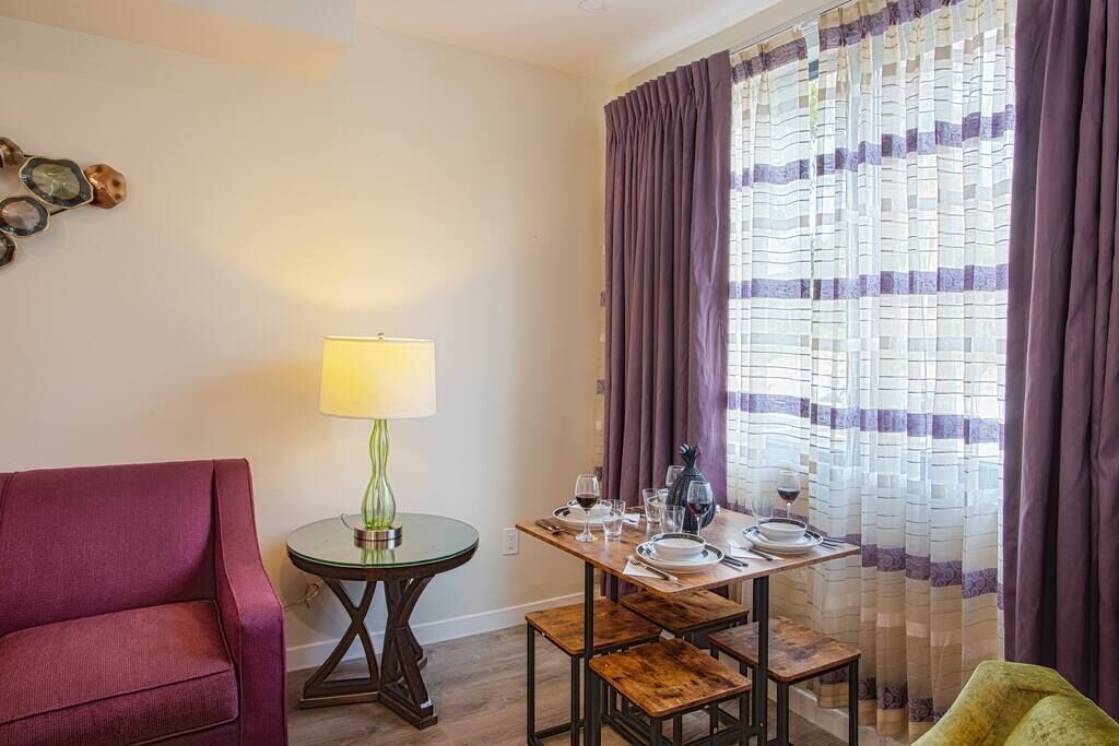 A dining area with a table set for two, a lamp, and a chair.