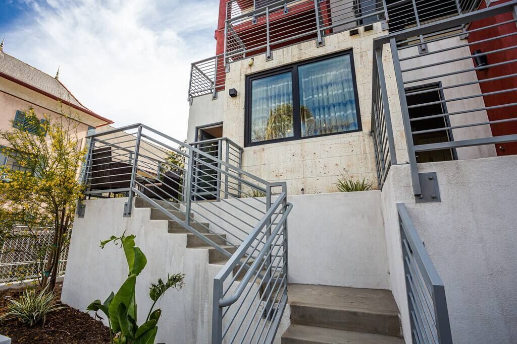 A modern building with a staircase leading to a second floor, surrounded by a white wall and metal railings.