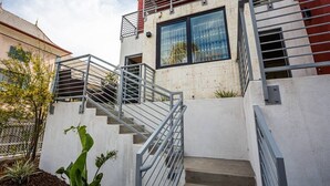Een modern gebouw met een trap die naar een tweede verdieping leidt, omgeven door een witte muur en metalen hekwerk.