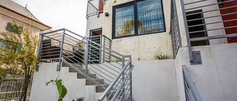 A modern building with a staircase leading to a second floor, surrounded by a white wall and metal railings.