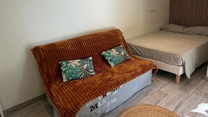Una habitación con sofá, cama, alfombra tejida y aire acondicionado.