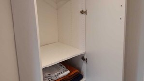 Un armario blanco con varios estantes y espacio para colgar.