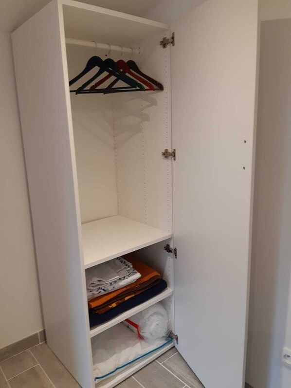 A white wardrobe with multiple shelves and hanging space.