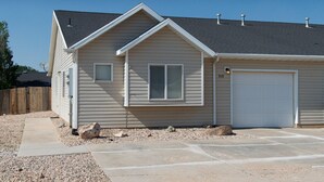Une maison de plain-pied avec un garage, un toit en pente et une allée gravillonnée.