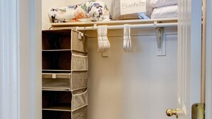 Un placard avec des étagères, une tringle pour suspendre des vêtements et une pancarte indiquant « Couvertures supplémentaires ».
