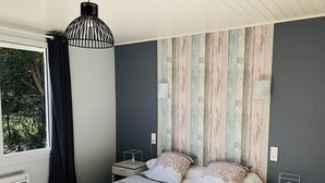 Quarto com cama, mesas de cabeceira, janela com cortinas e painel de madeira na parede.