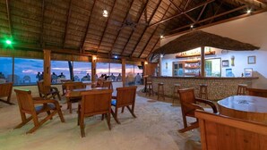 Un comedor interior con mobiliario de madera y una barra, con vistas al atardecer.