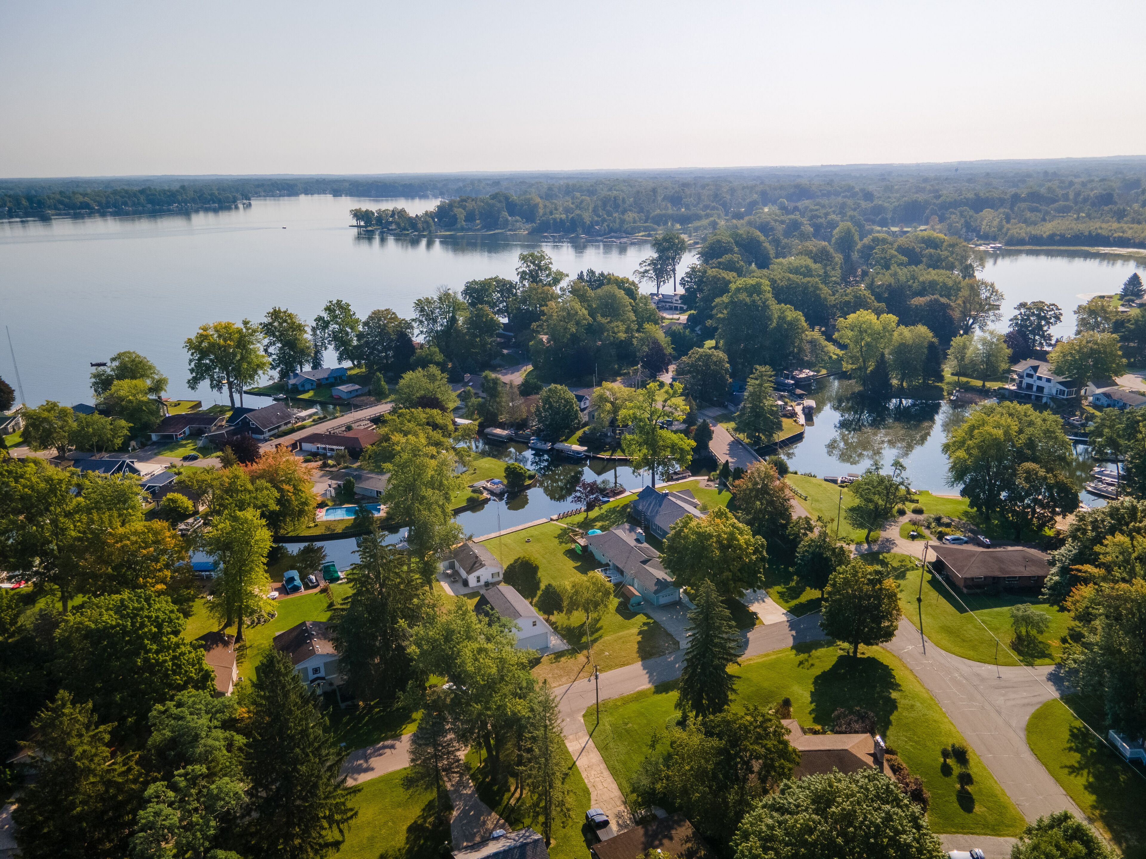 An aerial view of a residential area with houses, roads, and a lake.