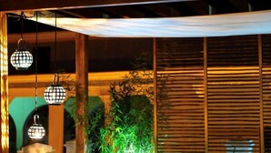 An outdoor seating area with a wooden bench and cushions, a potted plant, and hanging lanterns. - Splendid Colonial Villa with Rooftop & Jacuzzi (Cartagena)