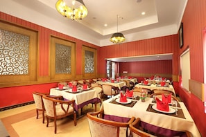 Comedor con varias mesas dispuestas para el servicio, sillas de madera y paneles decorativos en la pared.