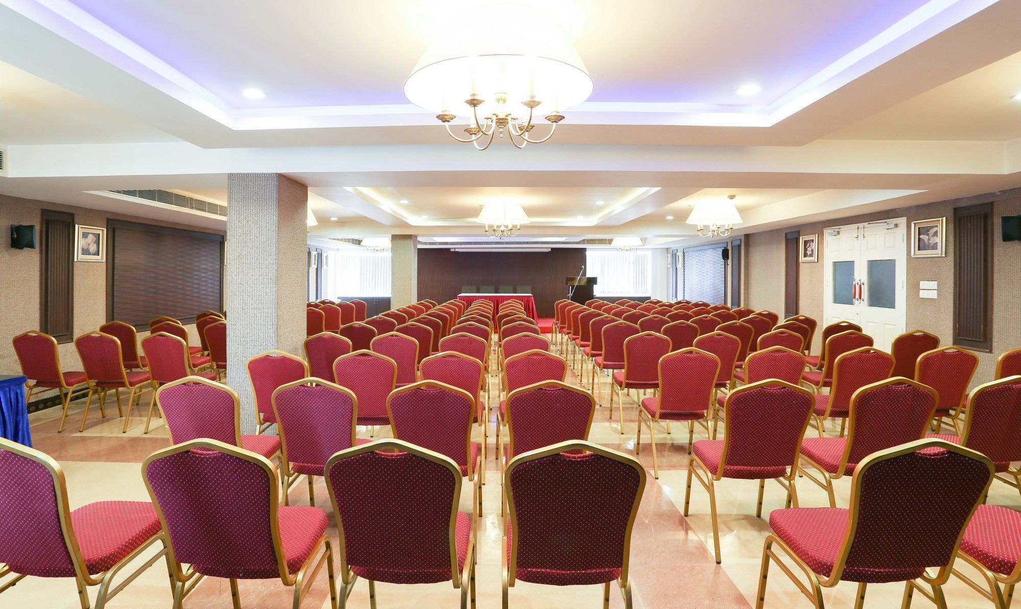 A conference room with rows of red chairs and a podium at the front.