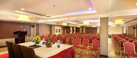 A conference room with a long table, red chairs, and a podium.